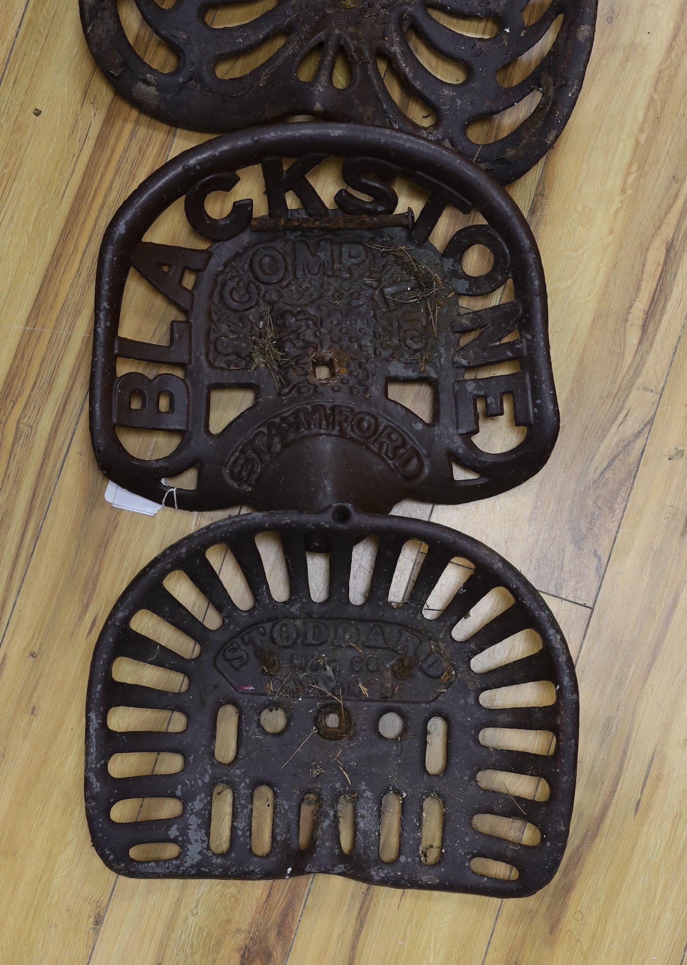 Four assorted cast iron and enamelled tractor seats